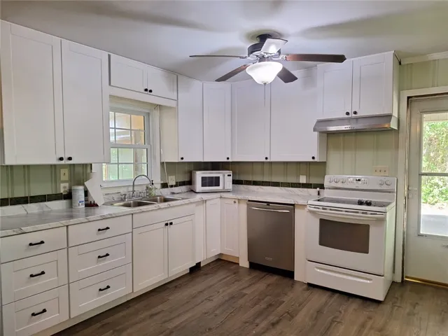 A well-appointed kitchen showcasing white cabinetry and durable wood flooring.