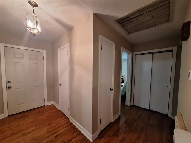 Rich hardwood flooring guides you through this functional hallway, featuring convenient access to various rooms and an attic hatch.