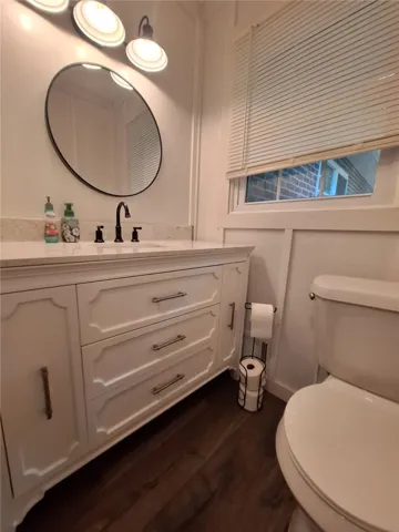 A well-appointed bathroom features a sleek vanity, an elegant round mirror, and a convenient window.