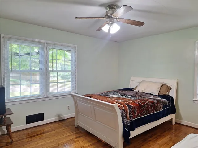 Hardwood flooring and a refreshing ceiling fan create comfort in this peaceful sleeping area.