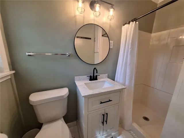 Step into a renovated bathroom featuring a modern vanity and clean shower stall.
