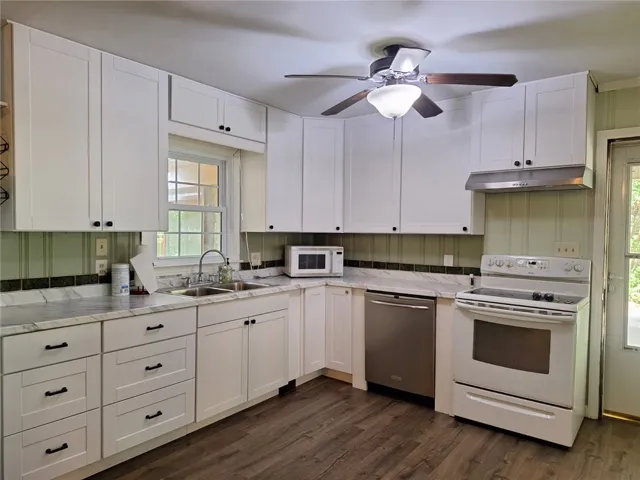 A well-equipped kitchen features ample white cabinetry, sleek countertops, and modern appliances.