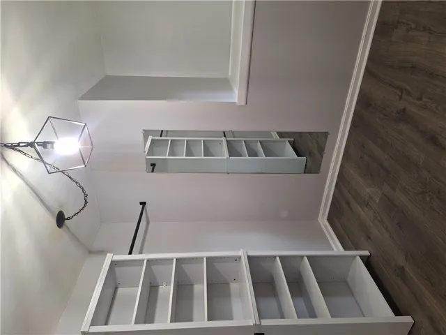Customizable shelving and rich wood flooring elevate this organized closet space.