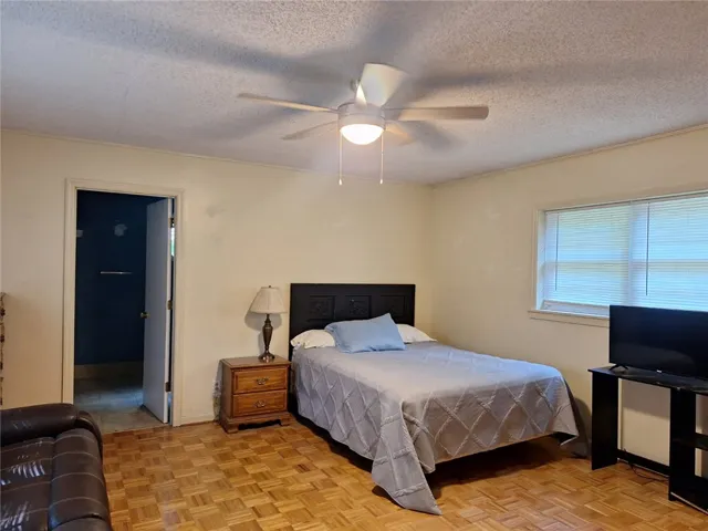 Well-lit sleeping quarters with rich parquet flooring and a classic ceiling fan.
