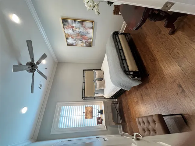 Hardwood flooring and crown molding highlight this comfortable bedroom, ideal for peaceful retreats.