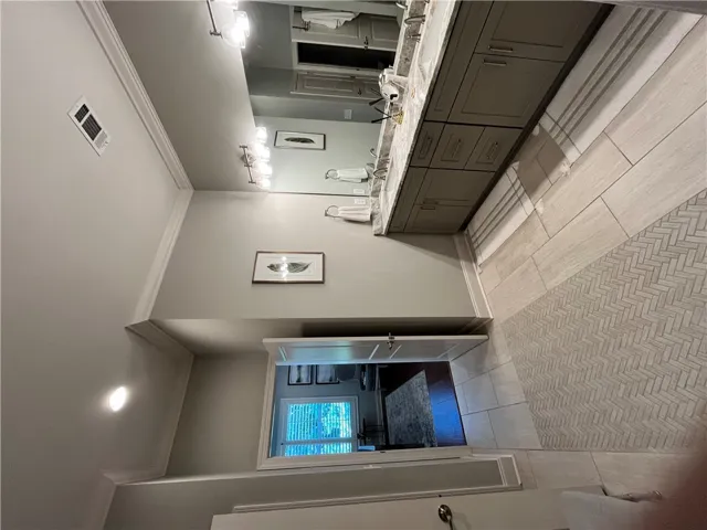 A refined bathroom featuring a long vanity and a beautifully tiled floor.
