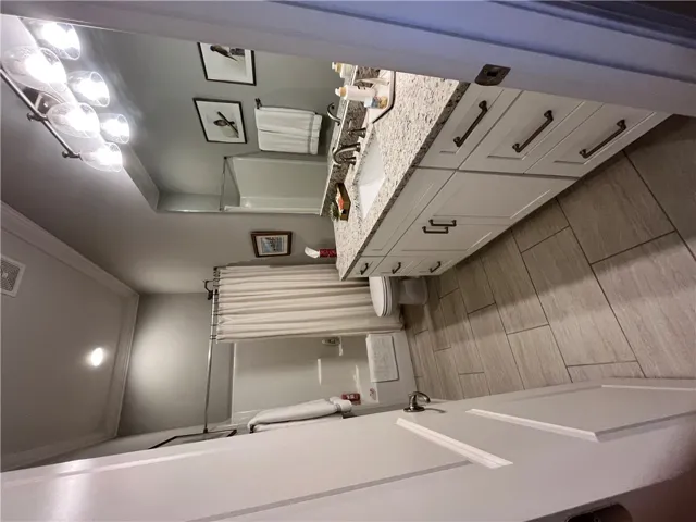 A well-appointed bathroom features a spacious vanity with a granite countertop and a combination shower-tub.