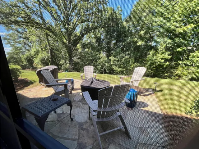 An inviting stone patio offers an ideal spot for outdoor gatherings amidst lush greenery.