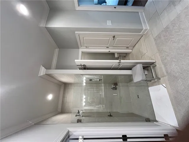 Step into this contemporary primary bathroom, featuring a spacious walk-in shower and sophisticated crown molding.