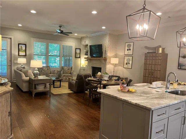 Hardwood floors flow through this open-concept living and dining space, highlighted by recessed lighting and a stately fireplace.