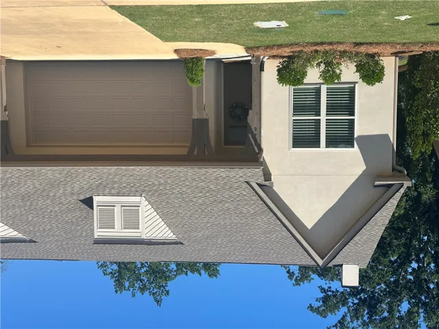 A well-maintained stucco facade with an attached garage offers a welcoming curb appeal.