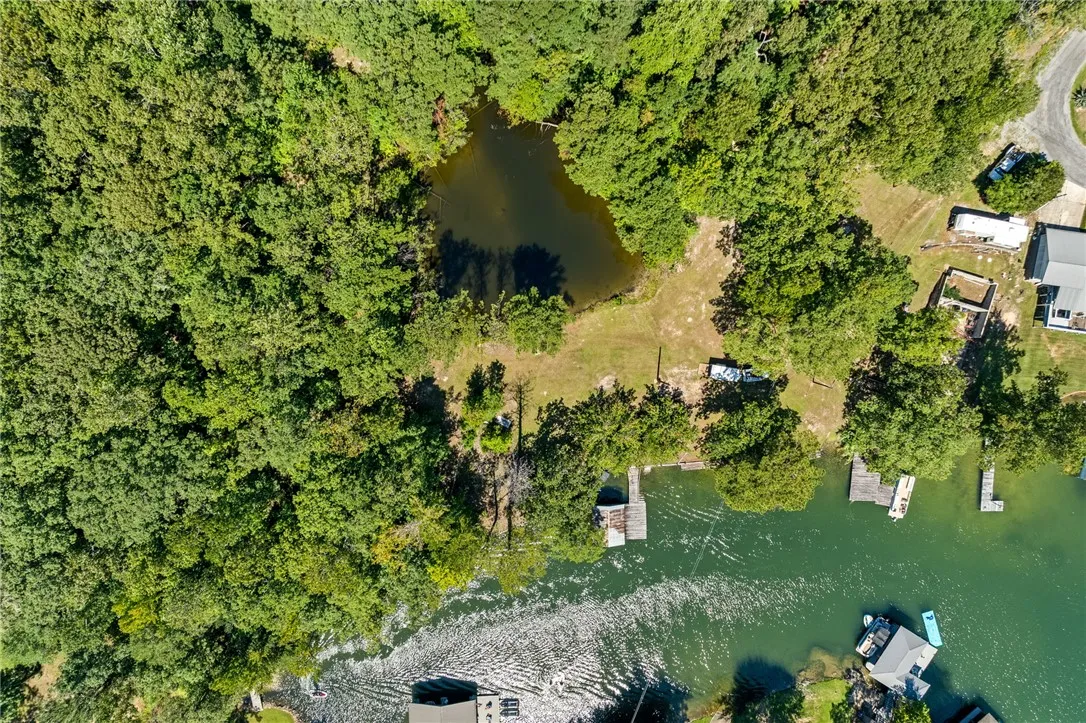 Aerial view showcasing a tranquil pond and direct access to a glistening lake with private docks.