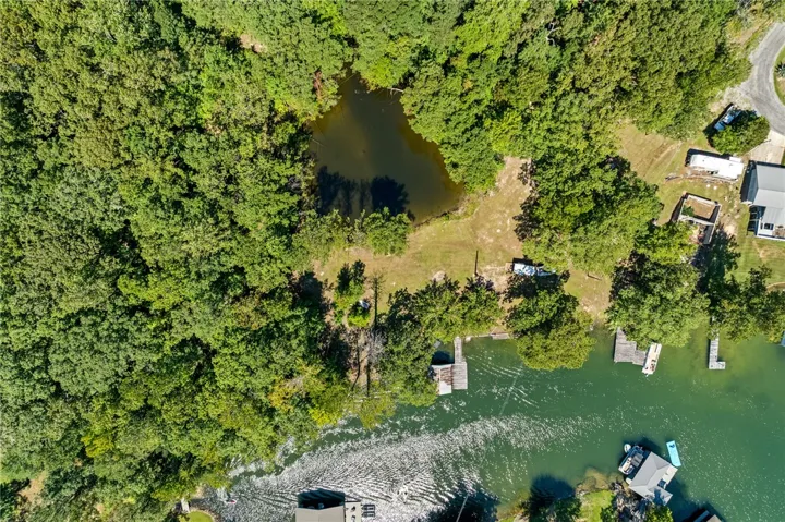 Aerial view showcasing a tranquil pond and direct access to a glistening lake with private docks.
