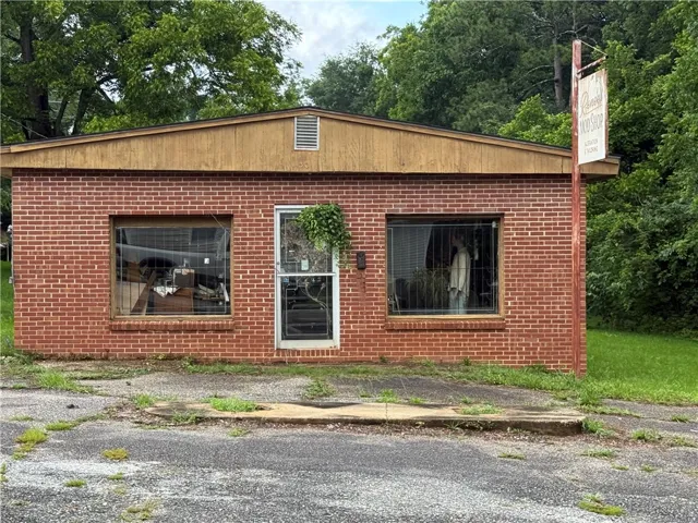 A brick building with prominent storefront windows awaits its next chapter, offering a flexible space for diverse ventures.