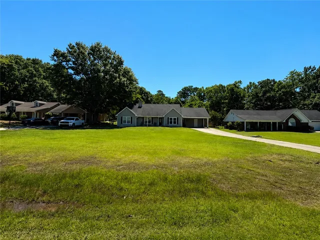 Nestled among green trees, a charming home with a winding driveway and abundant yard space awaits.