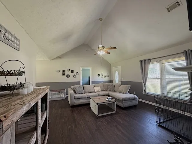 A comfortable living area features vaulted ceilings, rich hardwood flooring, and abundant natural light.