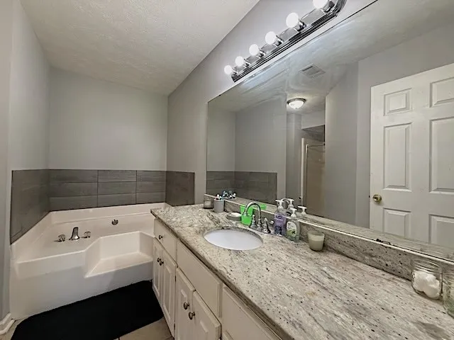 A well-appointed bathroom offers a corner soaking tub and an extended vanity with a single basin.