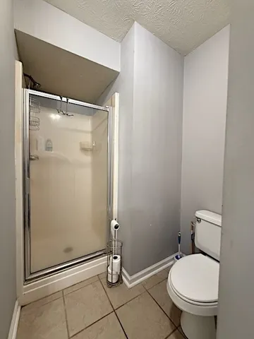 Functional full bathroom featuring a glass-enclosed shower and durable tiled flooring.