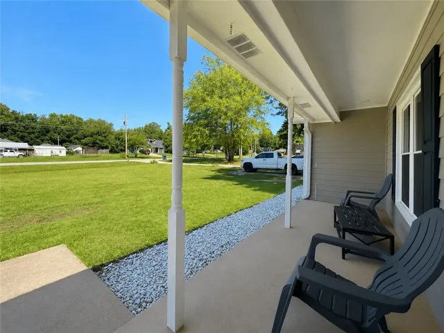 A welcoming covered porch offers serene outdoor relaxation with a view of the verdant yard.