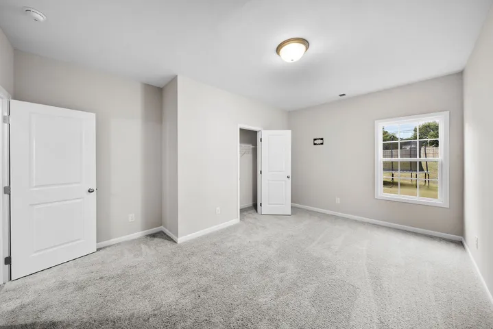 A well-lit bedroom provides ample space for relaxation with soft, plush carpeting and a convenient walk-in closet.