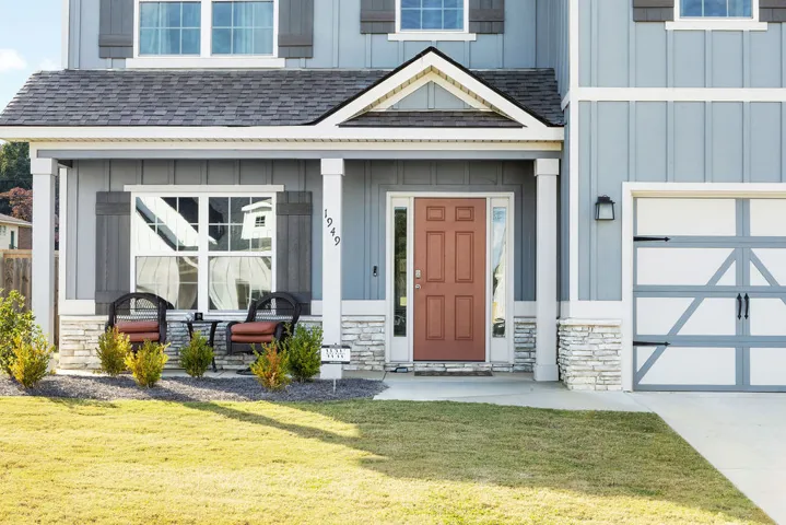 A welcoming facade with a covered porch, stone accents, and a distinctive garage door offers charming curb appeal.