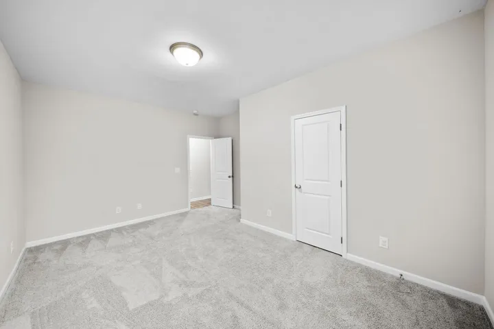 An inviting room features freshly installed carpet and a classic ceiling light fixture, ready for personalization.