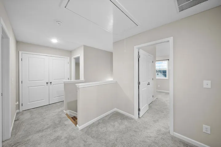 A well-lit landing features soft carpeting and white trim, leading to inviting rooms.