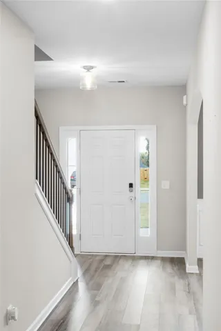 A welcoming entry features durable laminate flooring and a staircase leading to the upper level.