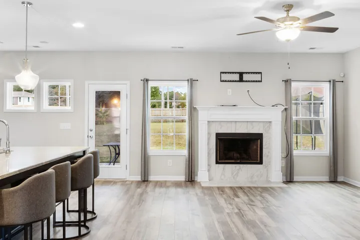 A well-lit living area features a charming fireplace with marble surround, complemented by durable hardwood flooring.