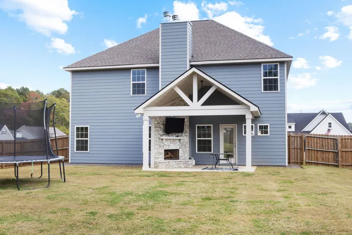 An inviting covered patio featuring a stone fireplace offers an ideal setting for outdoor enjoyment.