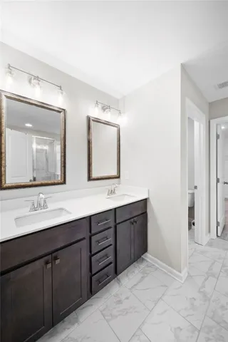Dual vanities with modern fixtures and spacious cabinetry highlight this well-appointed bathroom.