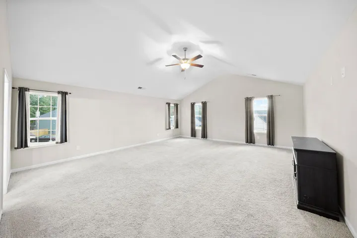A spacious room offers ample natural light and a comforting atmosphere with soft carpeting.
