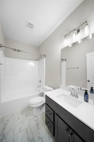 A well-appointed bathroom features a combined shower and tub, complete with a dark wood vanity and pristine white counters.