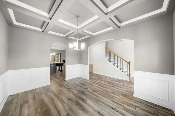 Coffered ceilings and wainscoting highlight this elegant dining area with rich hardwood flooring.