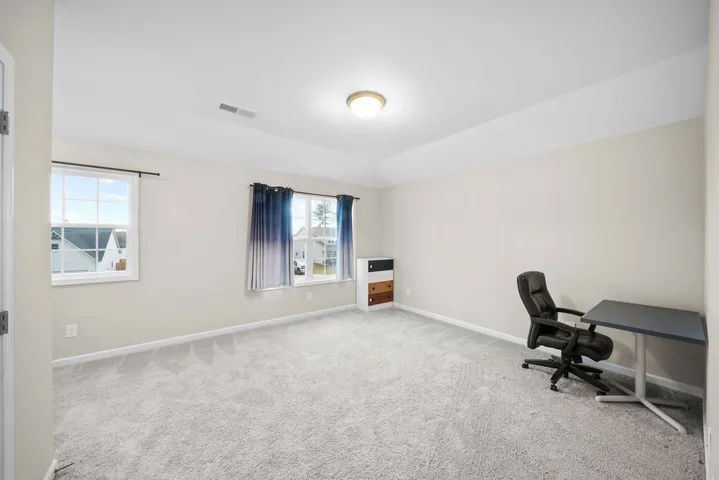 A quiet room features plush carpeting and multiple windows for abundant natural light.