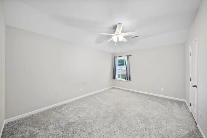 A spacious bedroom with a neutral color palette offers comfort and a well-lit ambiance.