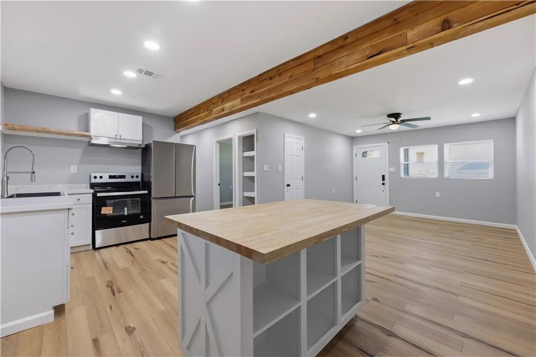 Blonde wood flooring unifies this open-concept kitchen and living area, highlighted by a large kitchen island with an eating bar.