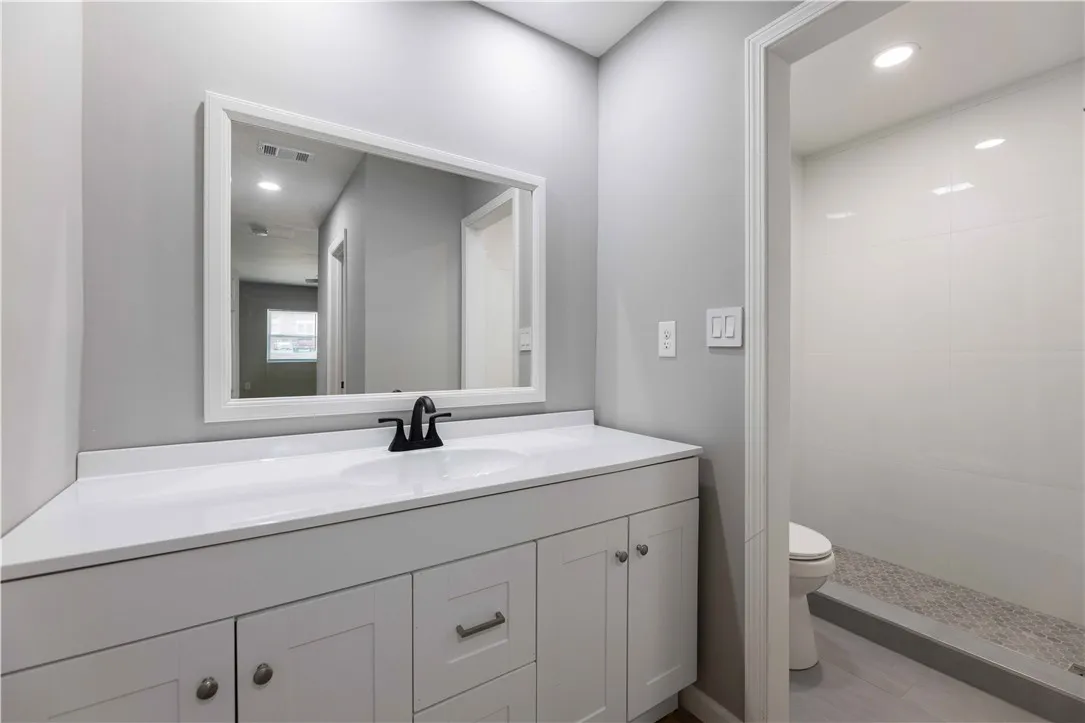 A well-appointed bath features a double vanity and an accessible walk-in shower with tiled walls.