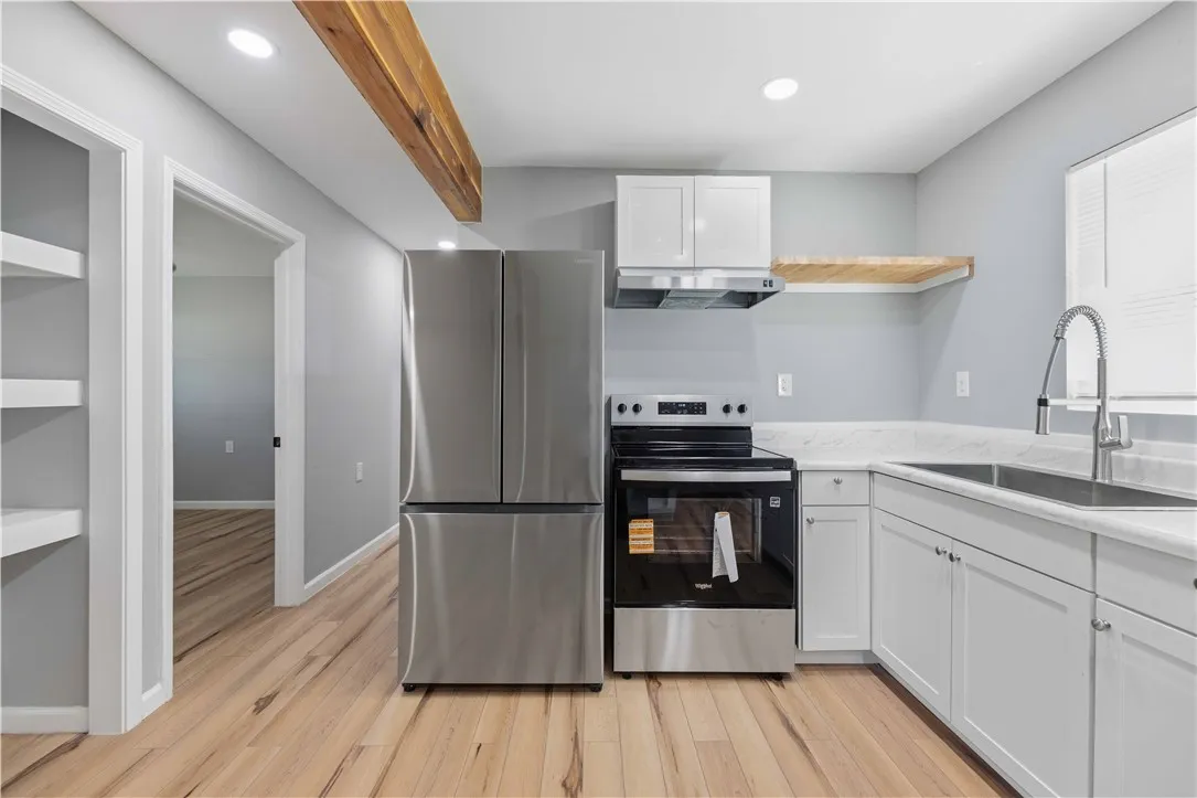 A streamlined kitchen showcasing stainless steel appliances, light wood flooring, and modern cabinetry.
