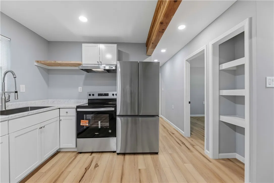 A well-appointed kitchen features sleek appliances, abundant cabinetry, and a charming wooden beam accent.