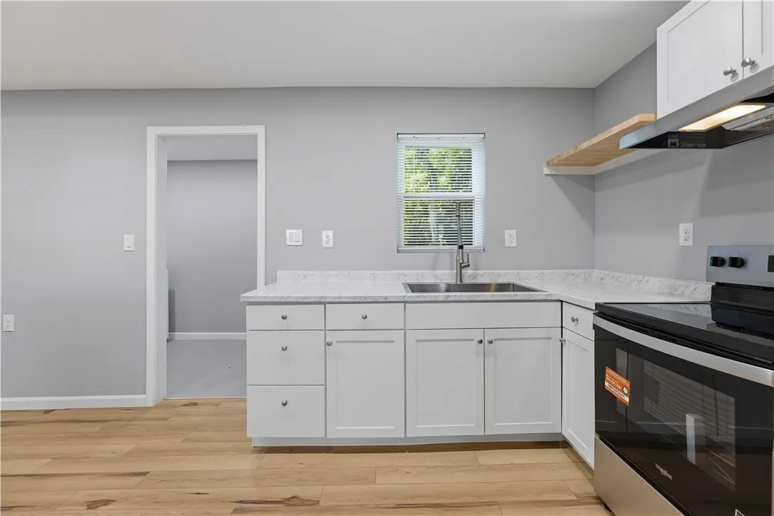 A well-lit kitchen with sleek white cabinetry, stainless steel appliances, and elegant hardwood flooring awaits.