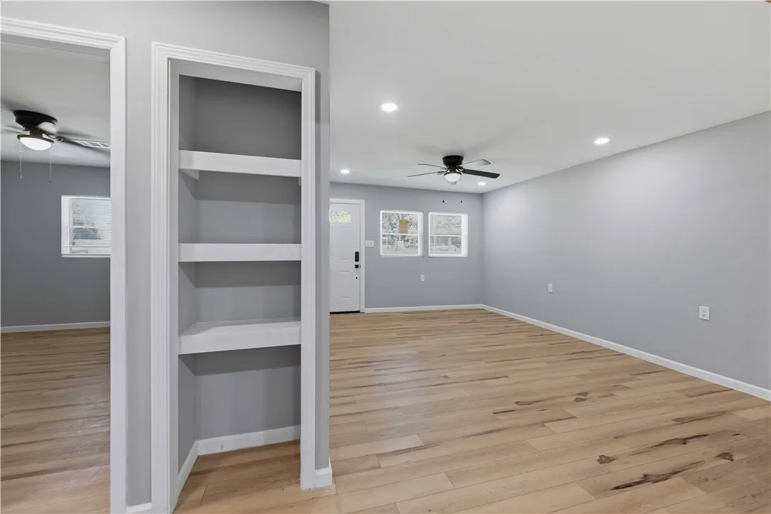Natural wood flooring complements the freshly painted walls and built-in shelving, ready for your personal touch.