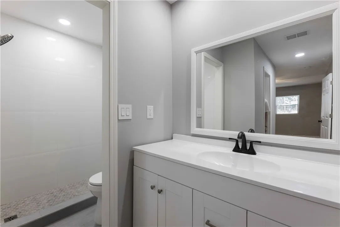 A well-lit bathroom features a spacious vanity and a walk-in shower with stone pebble flooring.