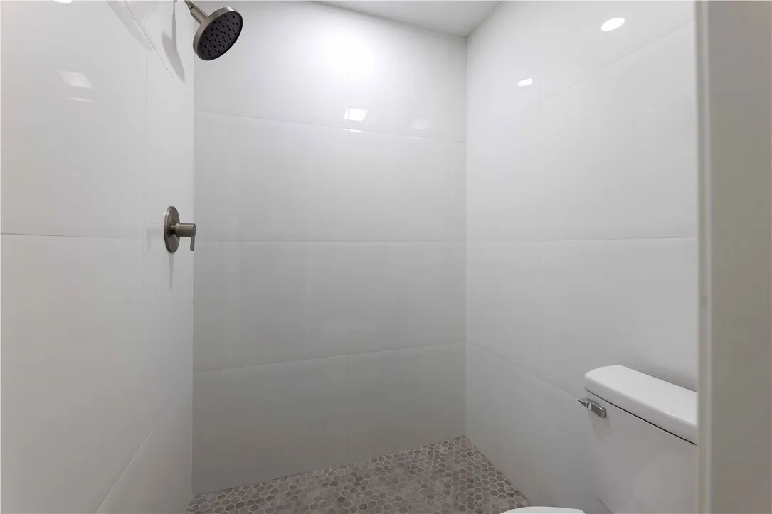 A modern shower space with clean lines and honeycomb floor tiling.