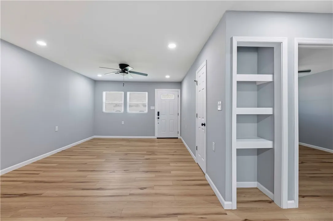 A welcoming interior with recessed lighting illuminates the warm plank flooring and offers a built-in shelving unit.