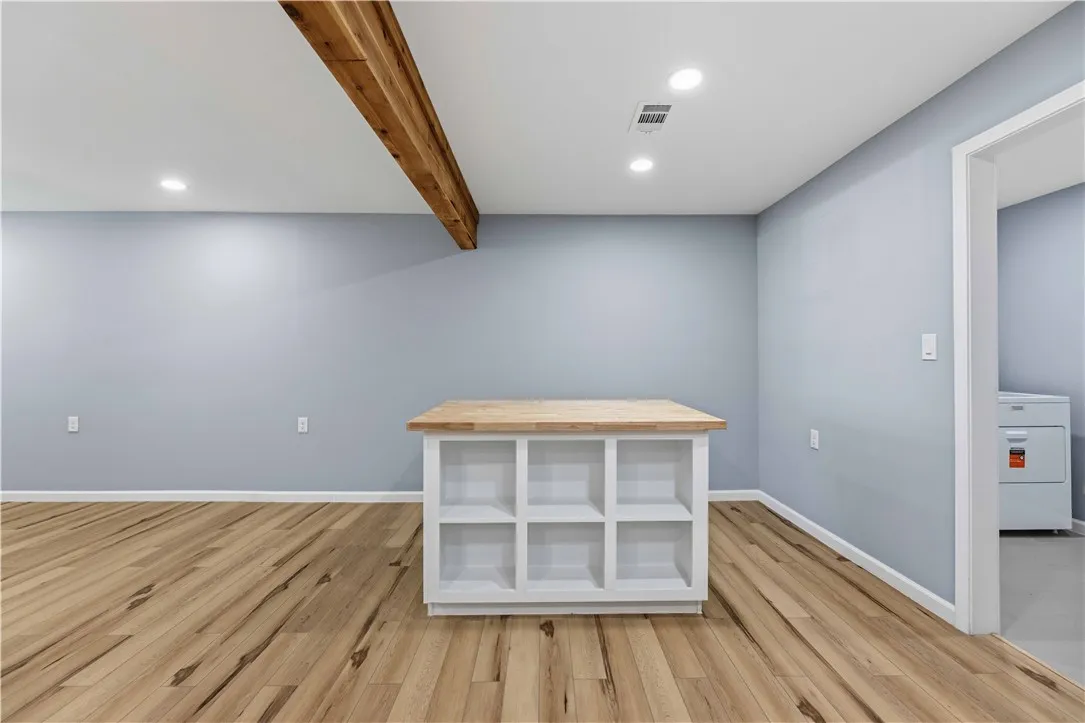 A versatile laundry area features a practical island with shelving, illuminated by recessed lighting.