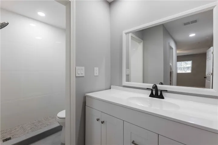 A well-lit bathroom features a spacious vanity and a walk-in shower with stone pebble flooring.
