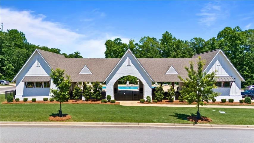 An inviting community clubhouse with classic white siding and a gated pool area, perfect for warm-weather enjoyment.