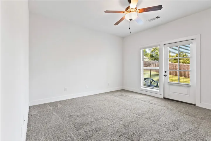 A well-lit bedroom features plush carpet and direct outdoor access through a glass-paned door.