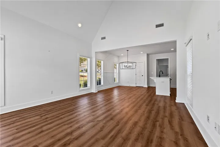 A generous gathering space with high ceilings and rich wood flooring defines modern living.